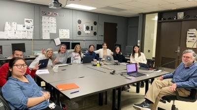 A group of smiling students poses for a photo with faculty Steve Viggiano