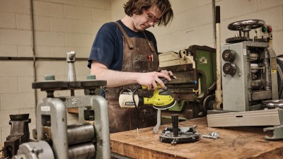 student uses an orbital sander on a metals project.