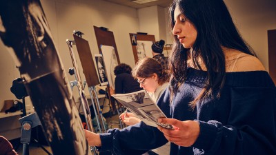 a student compares her drawing to a photo.