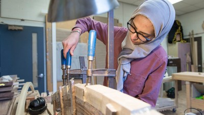 a student tightens bar clamps on a furniture project.