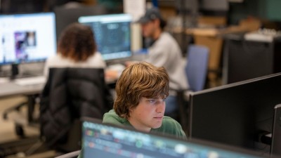 A student works at a computer, with a blurred background.