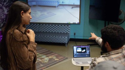 A student points at a projection created on a wall.