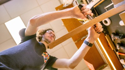 An upward view of an RIT student working with hand tools in the furniture design studio.