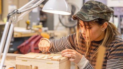 An RIT student uses hand tools on a furniture design project.