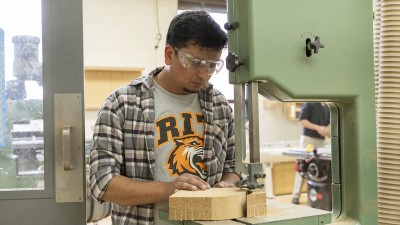 An RIT furniture design MFA student operates machinery in the program's studio.