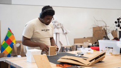 A student works with cardboard materials to make a sculpture.