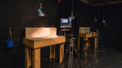 Stop motion film set in a black room with wooden stages and lights hanging from the ceiling