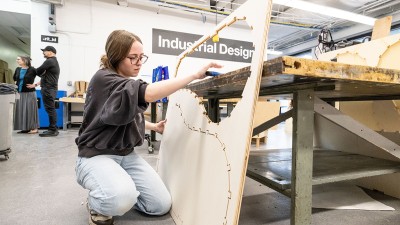 A student works with a piece of plywood with a shape cut out of it. Photo by Scott Hamilton/RIT