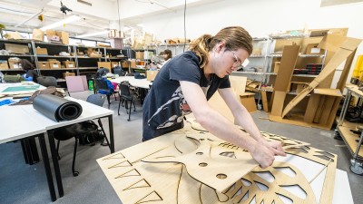 A student works with a piece of wood on a desk. Photo by Scott Hamilton/RIT