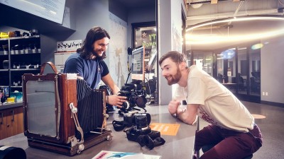 A Cage employee shows camera equipment to another student.