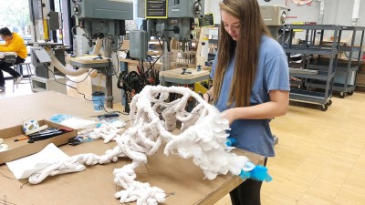 student works on a project with wires and feathers in a maker space.