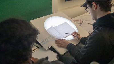Students draw on light tables.