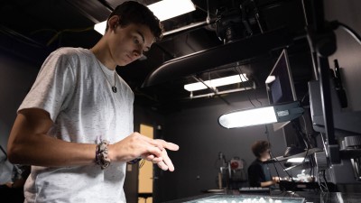 a student places small white beads down on a glass surface.
