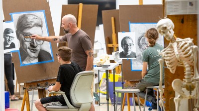 a faculty member gives feedback on a student's portrait drawing.
