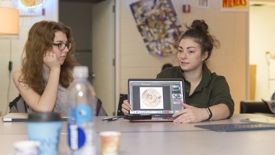 A student presents her laptop screen to a group.