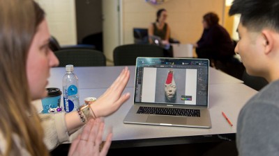 person gives feedback to a student's artwork on a laptop.