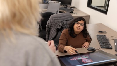 two people talk at a work station.