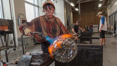 A student lights a torch to a glass object.