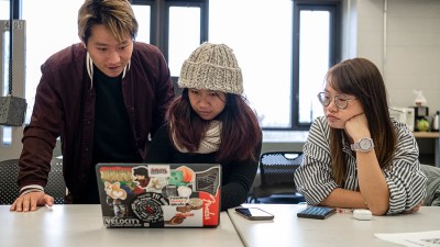 Students huddled around a computer to look at the screen.