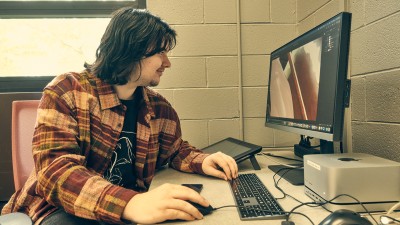 An RIT illustration students works at a computer station.