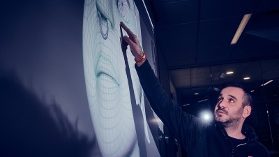 Kevin Bauer points to a character model projected on a screen.