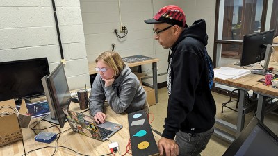 Faculty Mike Strobert works with a student at a computer in the new media design workshop.