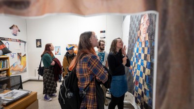 student looks at a quilt-styled artwork.