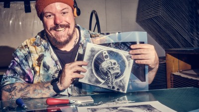 A student holds up prints they made in the printmaking studio.