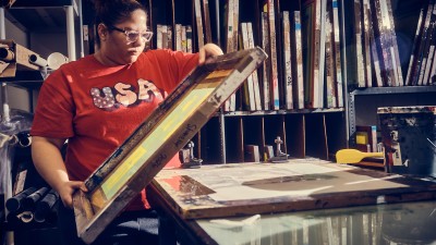 A student gets ready to set a plate down on a surface in the printmaking studio.