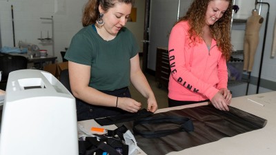 Two students work with soft fabrics side-by-side.