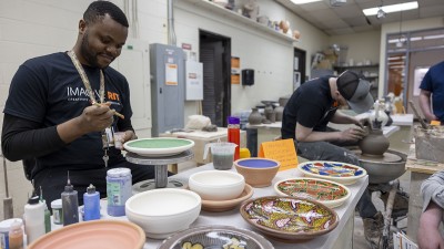 A ceramics MFA student paints a vessel he made.