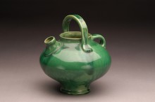 Green ceramic teapot with gold accents and a movable handle 