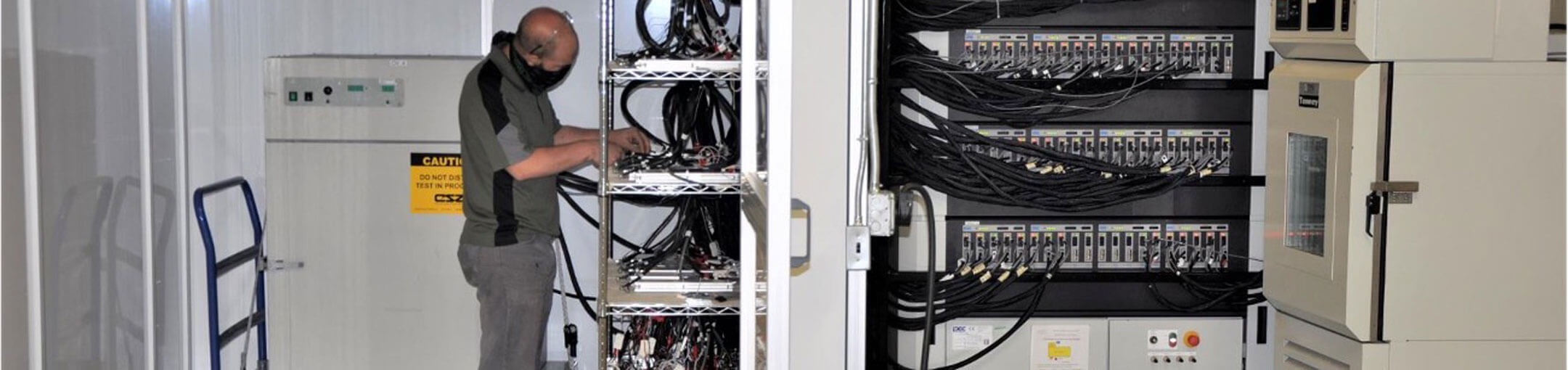 Man working at a rack of batteries.