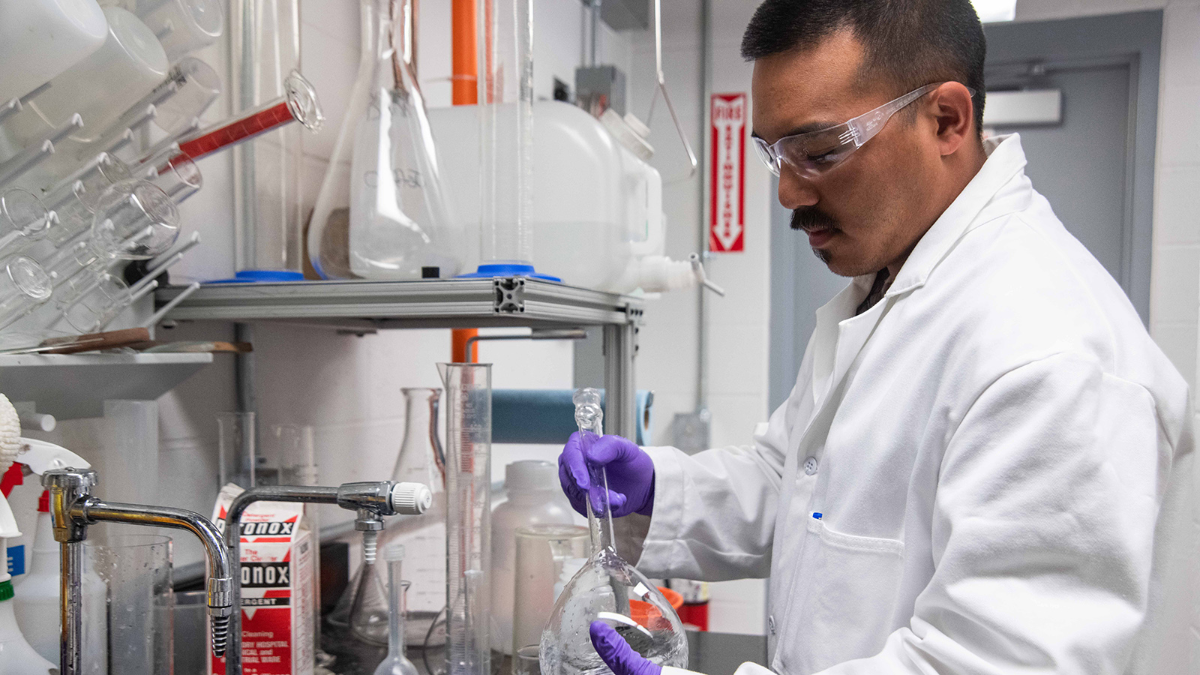 Man in a lab coat cleaning lab equipment in a laboratory setting