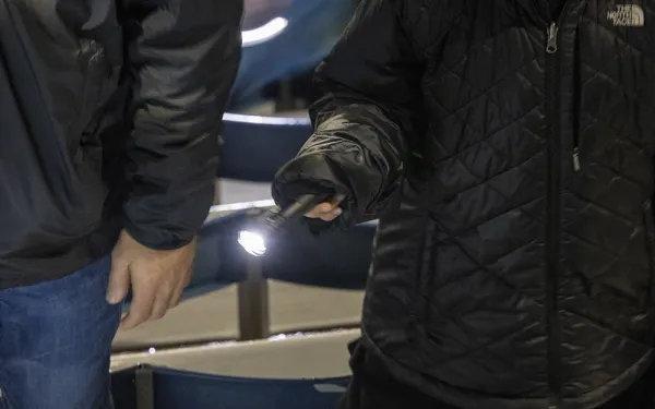 Big Shot participants point a flashlight at Highmark Stadium seats.