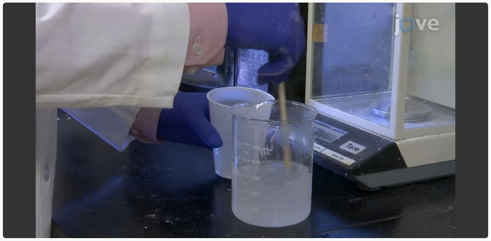 video screenshot showing a researcher mixing a cloudy liquid in a beaker.