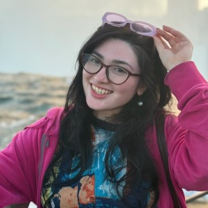 headshot of student in a pink sweater on a beach