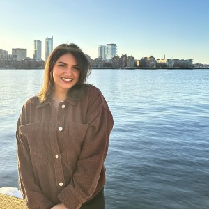 Student smiling in front of the rochester skyline and a body of water