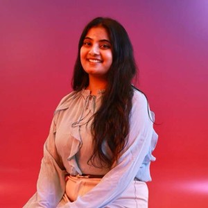 Professional shot of pravallika sitting on a stool with red/purple gradient backgrop
