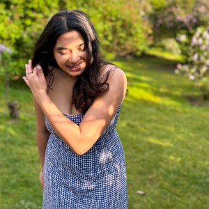 A female student looking down and smiling at the grass.
