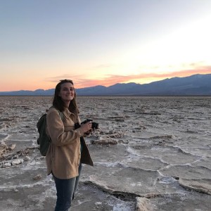 student on a beach with a camera in her hands