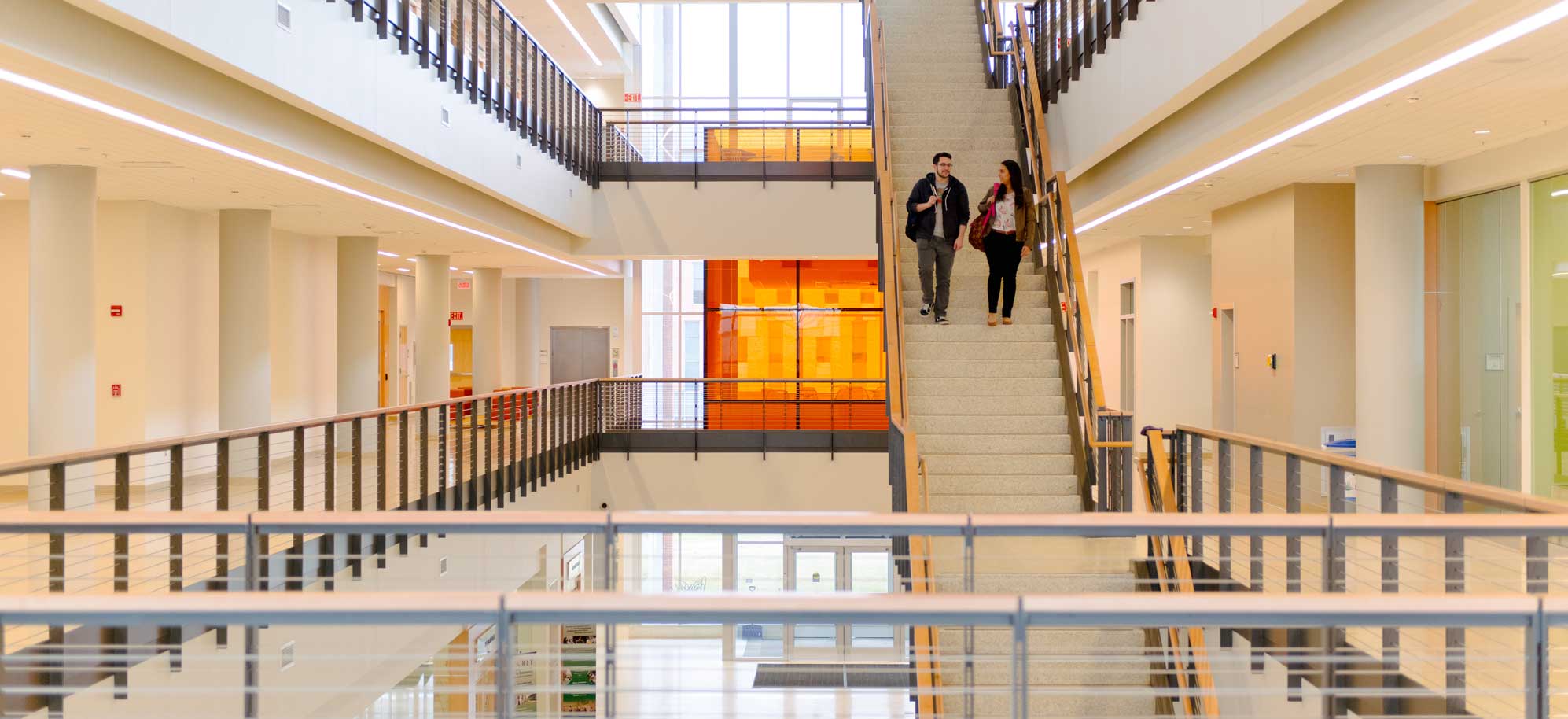 Two people walking down an open staircase