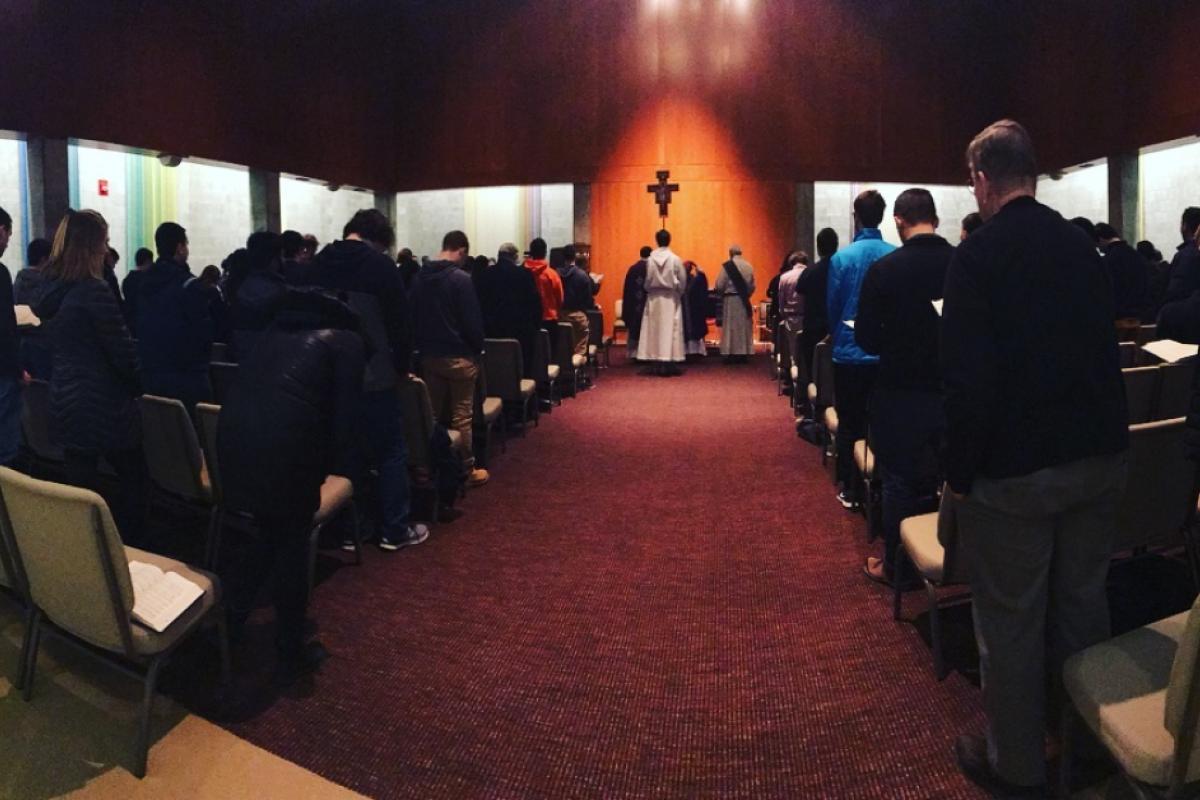 Members of the campus community participate in a Newman Catholic worship service in a chapel setting.