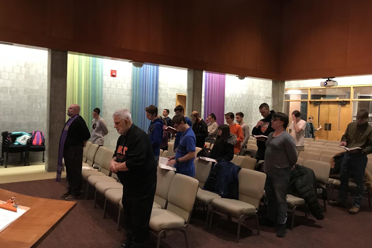 Students and community members stand in a campus worship space during a service hosted by The TABLE Lutheran-Episcopal Campus Ministry.