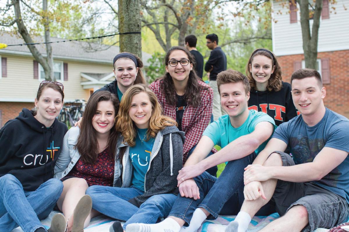 Students participating in Cru at RIT sit together outdoors during a campus gathering.