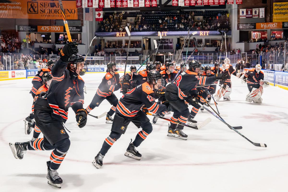 RIT hockey players skate onto the ice during pregame introductions in front of a packed arena crowd.
