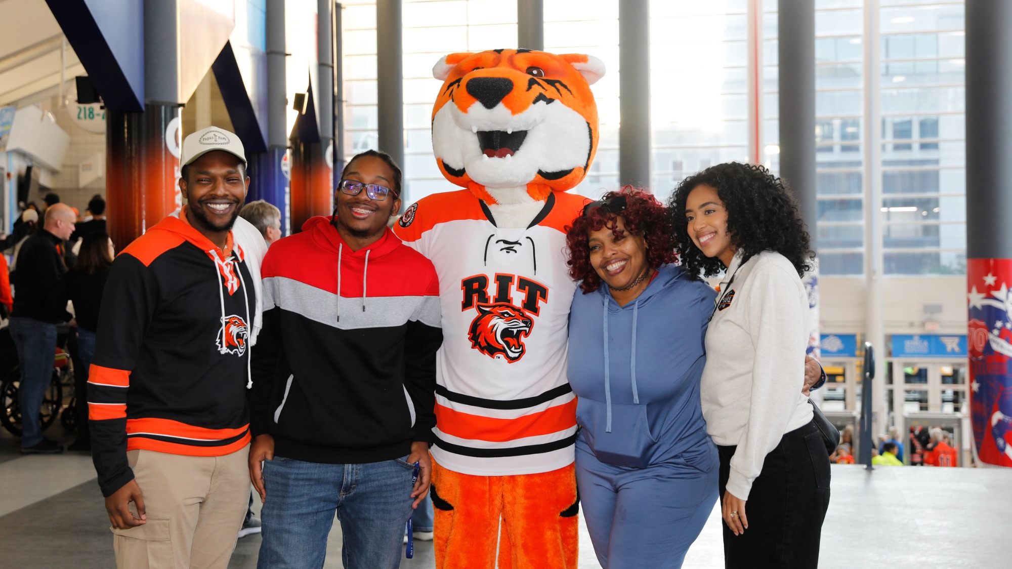Visitors stand with Spirit the Tiger in the arena concourse during an RIT hockey event.