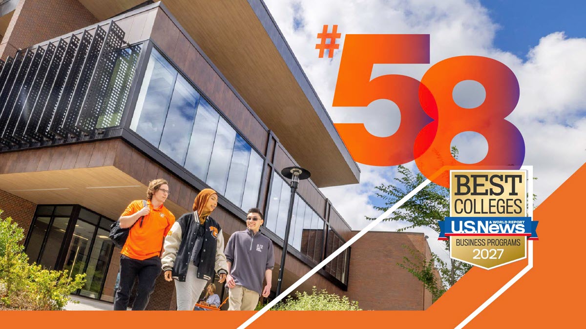 Students standing outside a campus building, chatting and enjoying the sunny weather.
