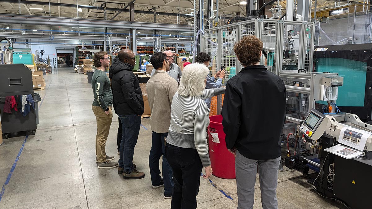 A group of visitors touring an industrial facility and examining manufacturing equipment.