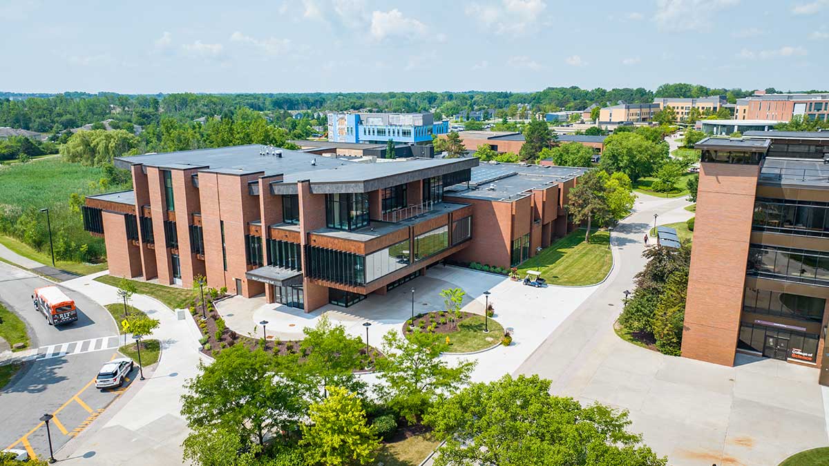 An aerial view of a modern academic campus with brick buildings and green surroundings.